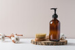 Liquid soap or lotion in glass jar container on wooden podium surrounded by cotton buds. Natural cosmetics concept