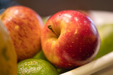 Fototapeta  - Um cesto plástico com frutas higienizadas com uma maçã vermelha em destaque. Macrofotografia.