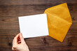 Hand holds blank paper against envelope for letters. Space for text, top view