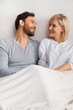 Portrait image - young attractive couple looking at each other, lay in home bed. Blond woman, brunette bearded man in love, relationship, happy family, waiting child concept.