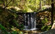 Górski wodospad w lesie. Czysta górska woda spływa po murze z kamieni.