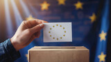 Fototapeta  - A person's hand is inserting a ballot with stars similar to the EU flag into a voting box, with EU flag backdrop The image conveys voting concept in the European Union context