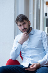 Wall Mural - portrait d'un beau jeune homme de 25 ans, assis au bureau. Il est barbu et porte une chemise