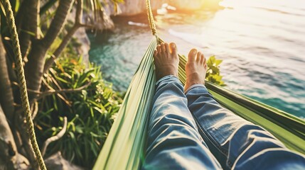 Canvas Print - Backpacker relaxing in a hammock by the sea, close-up on feet swaying, peaceful coastal view in background 