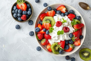 Wall Mural - Bird s eye view of fruit salad in bowl with strawberries blueberries kiwi and whipped cream on white table