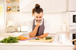 © VICTOR - A man is sitting at a kitchen counter with a tablet in front of him. He is looking at a carrot and a cucumber on the cutting board