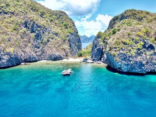 Canvas Print - Aerial view of a boat near a green tropical landscape on a sunny day