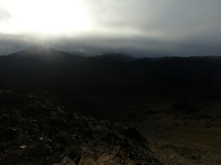 Canvas Print - Sun shining through clouds above mountain peaks