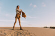 © SHOTPRIME STUDIO - Female traveler standing triumphantly on sand dune with backpack, enjoying breathtaking desert landscape view