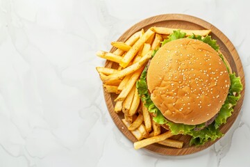 Wall Mural - Overhead view of half a classic burger with pork beef cheese mayo lettuce and fries on a wooden plate on a white kitchen counter