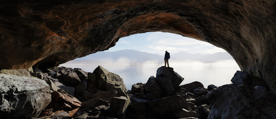 Wall Mural - adult adventurous man standing in a cave. 3d rendering mountain adventure artwork.