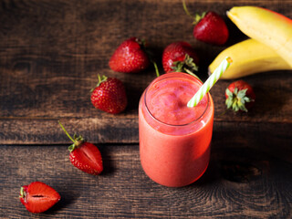 Wall Mural - a glass of strawberry banana smoothie with a straw on a wooden table