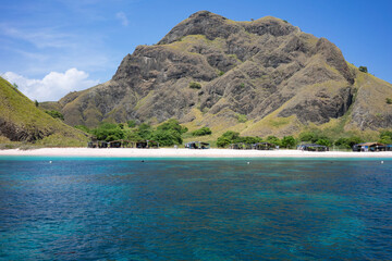 Wall Mural - Crystal clear turquoise waters meet a secluded pink sand beach under the towering hills of Komodo Island.