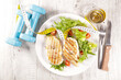 grilled chicken breast with lettuce, dumbbell and measuring tape