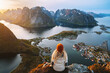 Woman hiking in Lofoten islands travel lifestyle in Norway, girl enjoying aerial view from Reinebringen mountain top active vacations famous spot destinations solo traveler outdoor adventure journey