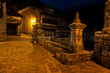 An old stone fountain on a quiet cobblestone street. The street is lit up with a yellow light at night, Barcena Mayor, Saja-Besaya Natural Park, Cantabria, Spain