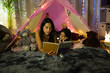 Mother and daughter bonding over reading in a diy tent with fairy lights, creating a cozy evening ambiance at home
