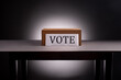 Voting box on desk on gray with dramatic lighting
