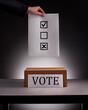 Рand in business suit holding ballot paper over voting box