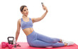 Slim, bodybuilder girl in a lilac tracksuit, sitting on the mat, she is chatting, cardio workout. Sports concept, fat burning and healthy lifestyle.