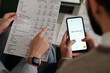 © pressmaster - High angle of hand of young unrecognizable woman pointing at sum in financial bill while her husband making calculations on smartphone