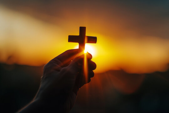 Christian Cross in Hand During Sunset Background