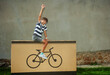 Happy teenage boy on bike gift box triumphantly raising arms
