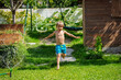Kid enjoy sprinkle of water while sprinting across a green lawn