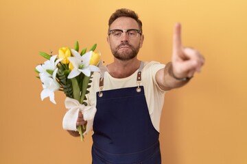 Sticker - Middle age man with beard florist shop holding flowers pointing with finger up and angry expression, showing no gesture