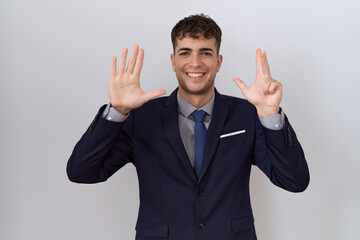 Wall Mural - Young hispanic business man wearing suit and tie showing and pointing up with fingers number eight while smiling confident and happy.