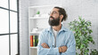 © Krakenimages.com - Handsome hispanic man with arms crossed standing in a modern office interior.