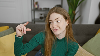 Canvas Print - Smiling young woman pointing something at the cozy living room of a modern apartment.