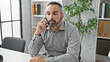 © Krakenimages.com - Handsome senior hispanic man with grey beard in an office setting talking on a smartphone