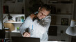 © Krakenimages.com - Hispanic male doctor feeling neck pain during a late night at the office, portraying workplace stress.