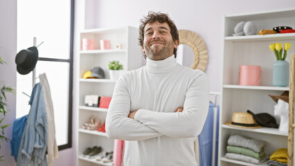 Sticker - Handsome young hispanic man with arms crossed standing in a modern fashion dressing room