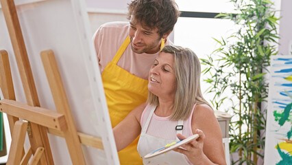 Canvas Print - Two confident artists, man and woman, enjoy drawing together with smiles in indoor art studio, while learning and painting