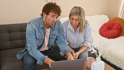 Wall Mural - Mother and son sharing a heart-warming tech moment on their home sofa, speaking and using a laptop together in their casual sitting