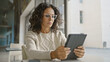 © Krakenimages.com - A mature hispanic woman focused on reading her tablet in a bright office interior.