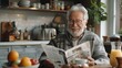 © Chand Abdurrafy - Smiling senior man sitting at the table reading newspaper, modern kitchen interior in light colors on background