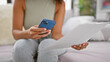 © Krakenimages.com - Smart woman engrossed in reading document on smartphone while sitting on sofa at home