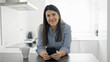 © Krakenimages.com - Young beautiful hispanic woman using smartphone leaning on the counter at the kitchen