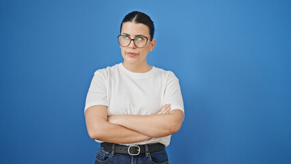 Sticker - Young beautiful hispanic woman with arms crossed looking upset over isolated blue background