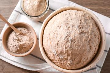 Wall Mural - Fresh sourdough in proofing basket and flour on wooden table, top view