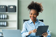© NanSan - Utilizing a tablet, a young African American woman in a blue formal shirt with afro brown hair works as a Market Research Analyst in a modern office.