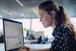 © Bora - woman looking at computer with graphs open on a laptop in a modern office