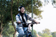 © Alfian Muzaki - Young cheerful hijab woman, wearing casual flannel riding bicycle bike on sidewalk in the city park enjoying being outdoors, look aside or ahead. People active urban healthy lifestyle cycling concept.