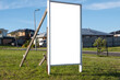 Blank white mockup background texture of a real estate board on a vacant lot of land.  Real estate advertisement for future homes property, sign in a neighbourhood with many residential houses.