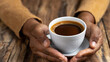 hands holding a cup of black coffee on wooden table in cafe