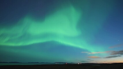 Wall Mural - A beautiful dance of the northern lights in the night starry sky above the sea. A timelapse video.