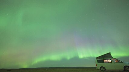 a spectacular dance of aurora borealis in the dark winter sky. a traveler's van with a tent in the f